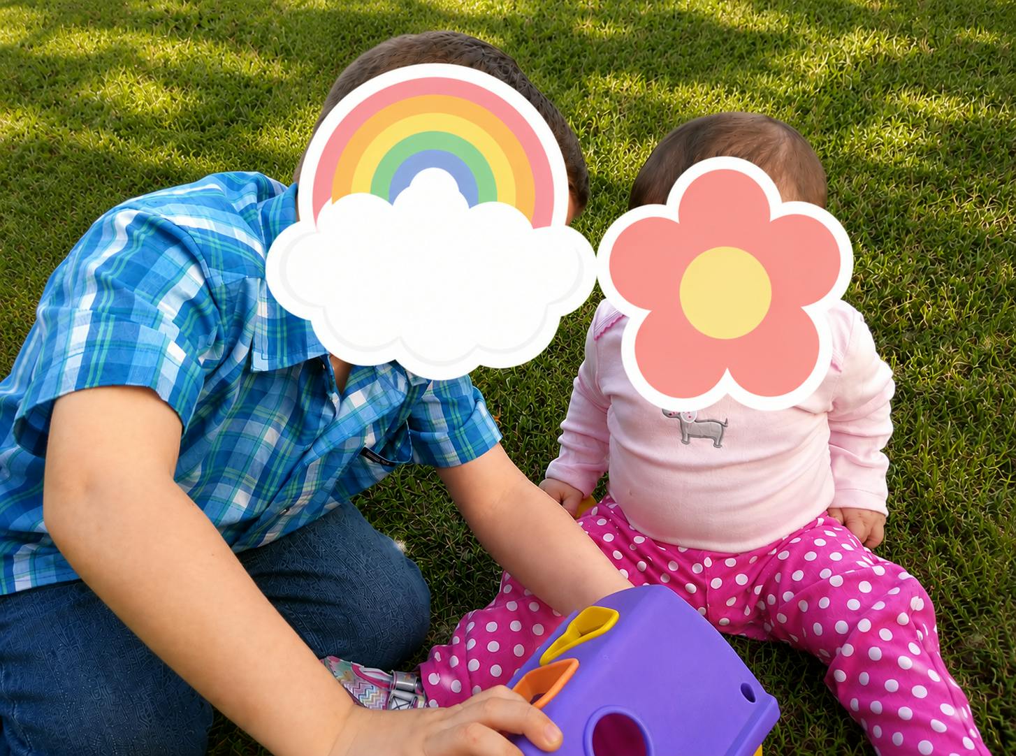 Child and infant playing with a toy on the grass