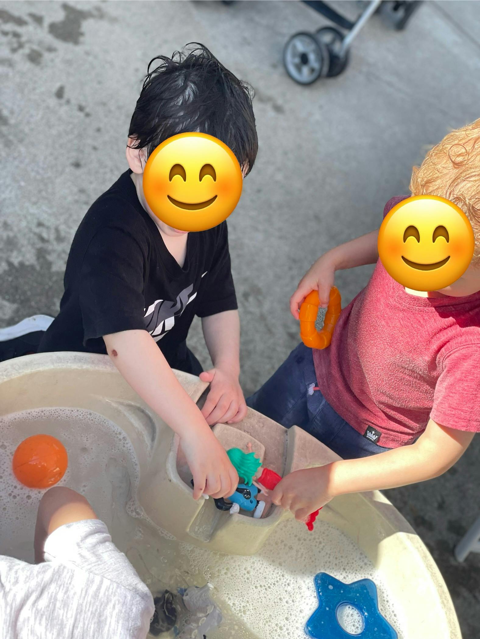 Two children playing with toys in a water table