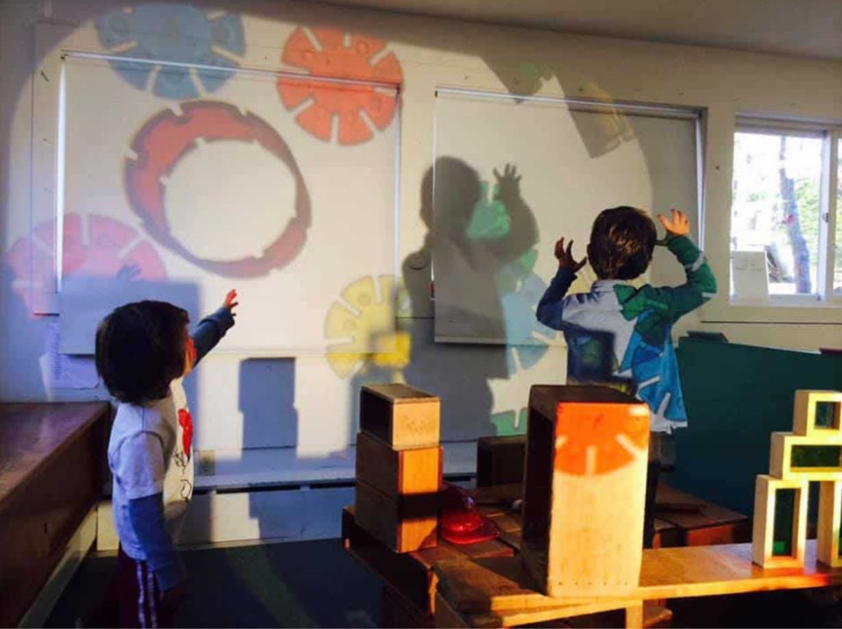 Two children interacting with light projections on a wall