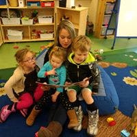 Adult reading a book to three children