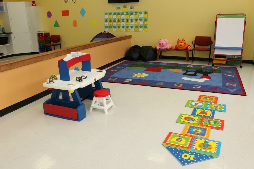 Playroom with a toy workbench, alphabet rug, and hopscotch mats
