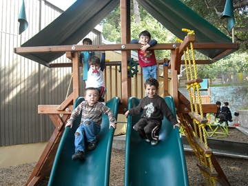 Children on a playground structure with two children on slides