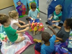 Children sitting in a circle playing with a craft