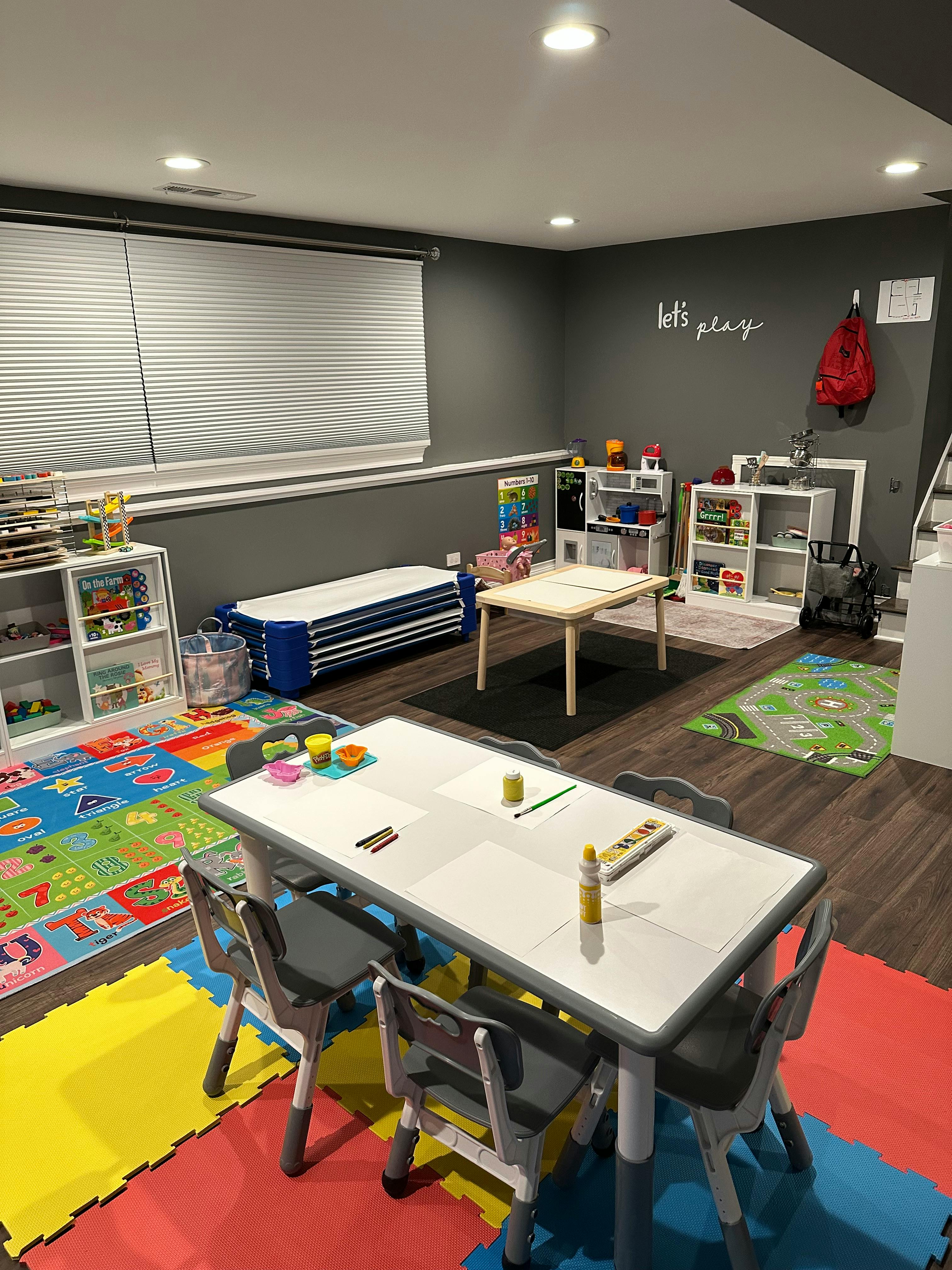 Playroom with multiple tables, chairs, and storage shelves