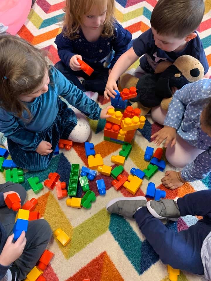Children playing with colorful building blocks on a patterned rug