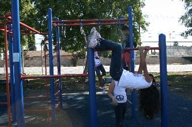 Child hanging upside down from monkey bars