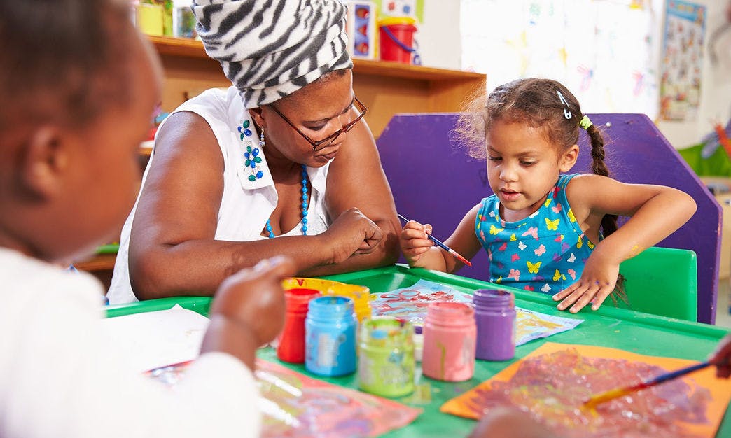 Adult and child painting at a table in a classroom