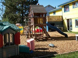Playground with a wooden play structure, slide, and playhouse