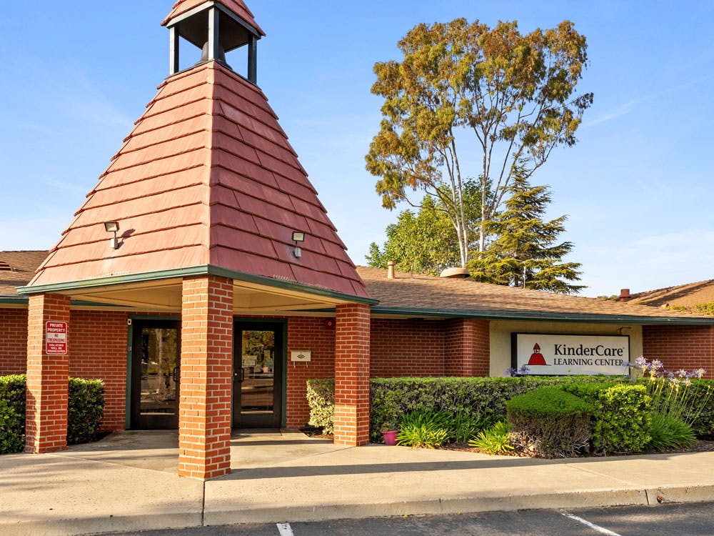 Brick building with a tall, red-tiled conical roof and a KinderCare Learning Center sign