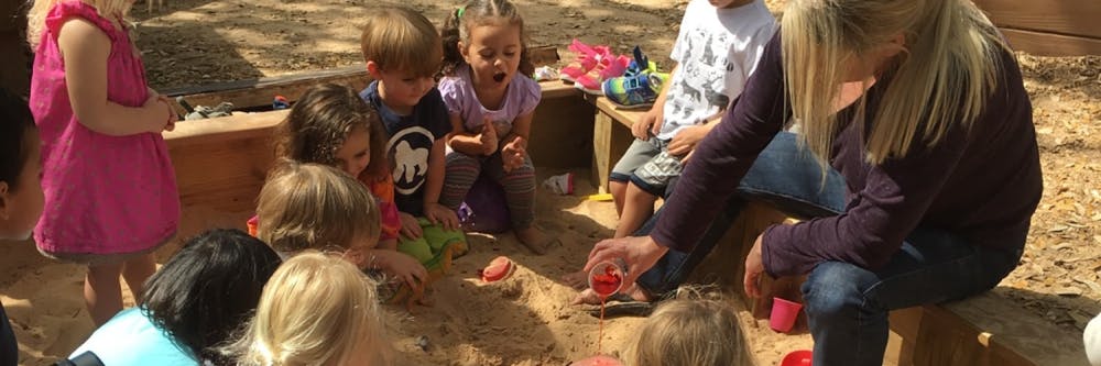 Adult and children playing in a sandbox