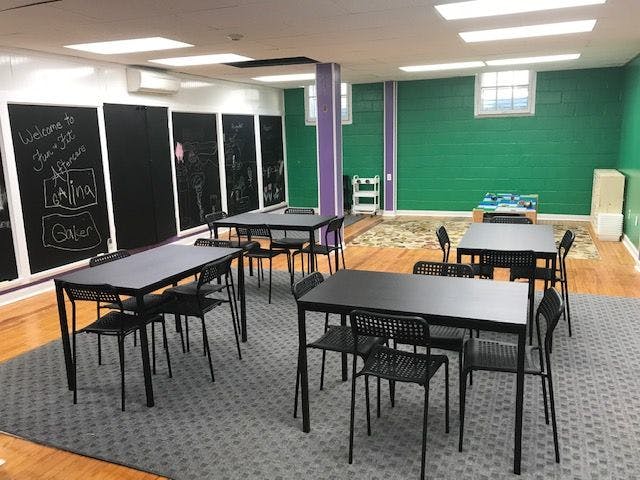 Classroom with tables and chairs, blackboards on one wall