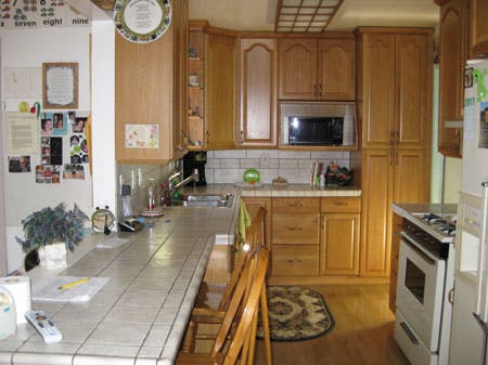Kitchen with wooden cabinets, white tile countertop, and appliances