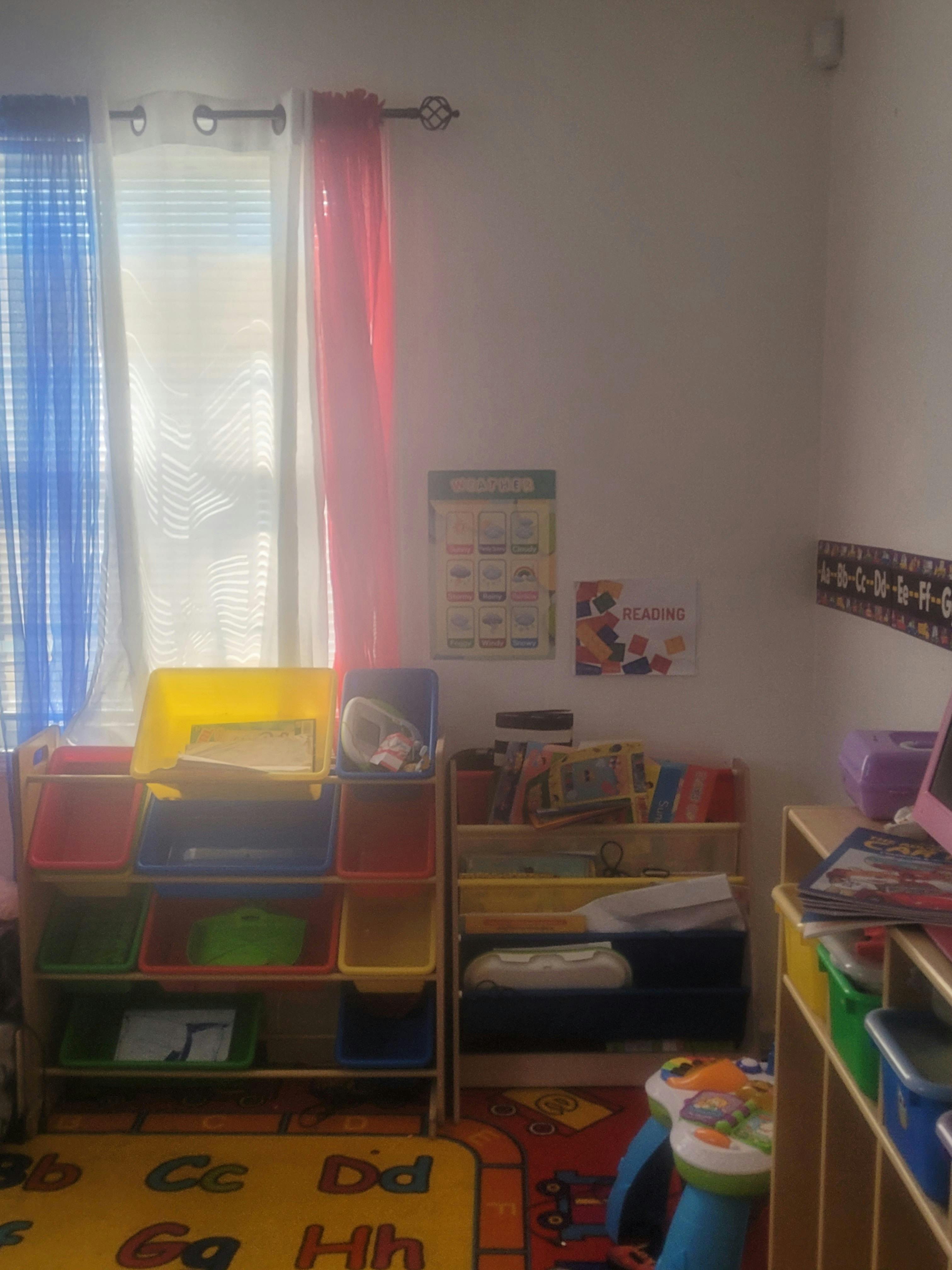 Classroom with colorful storage bins, bookshelves, and an alphabet rug