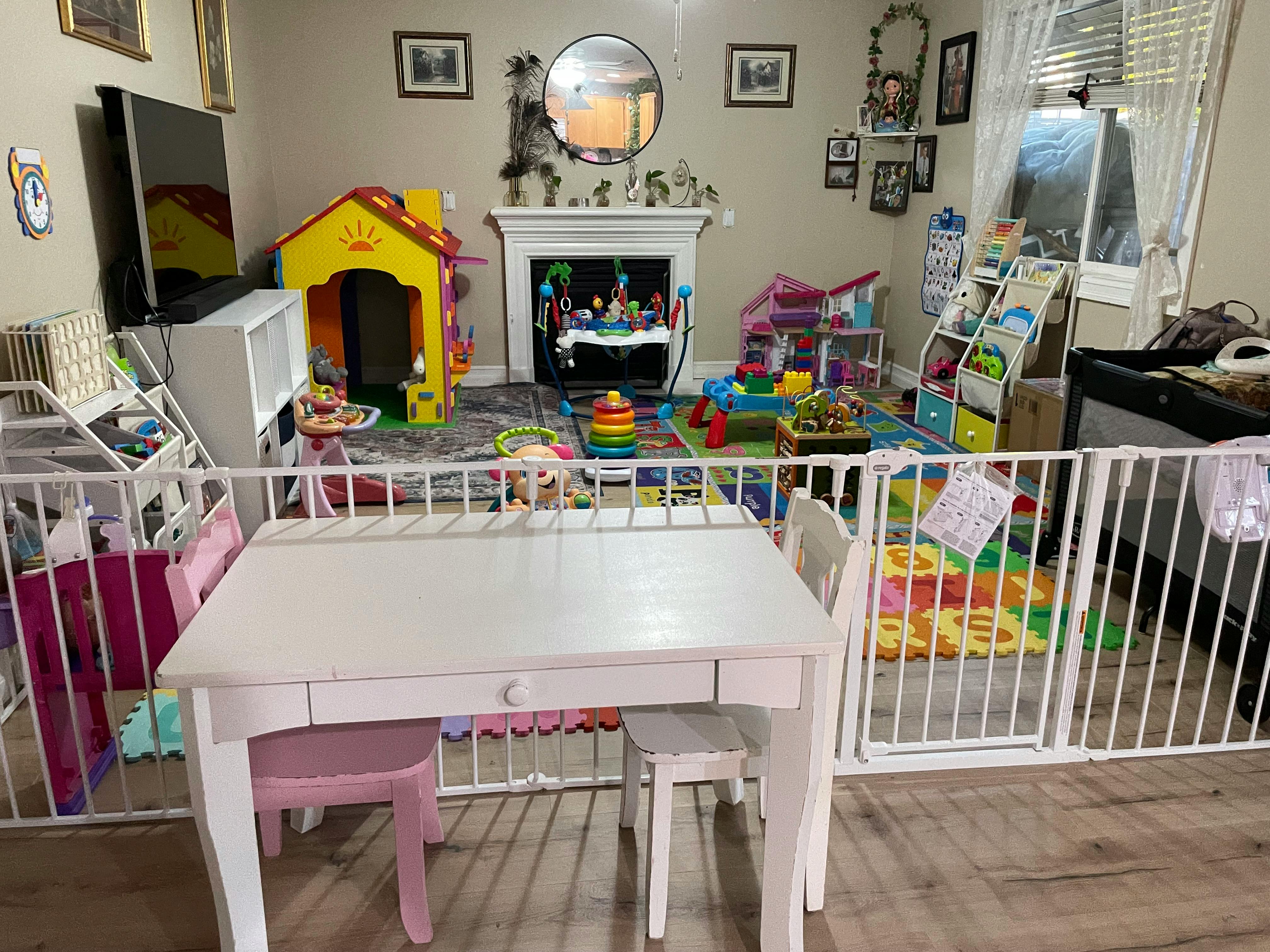 Playroom with a white table and chairs in the foreground, surrounded by a safety gate