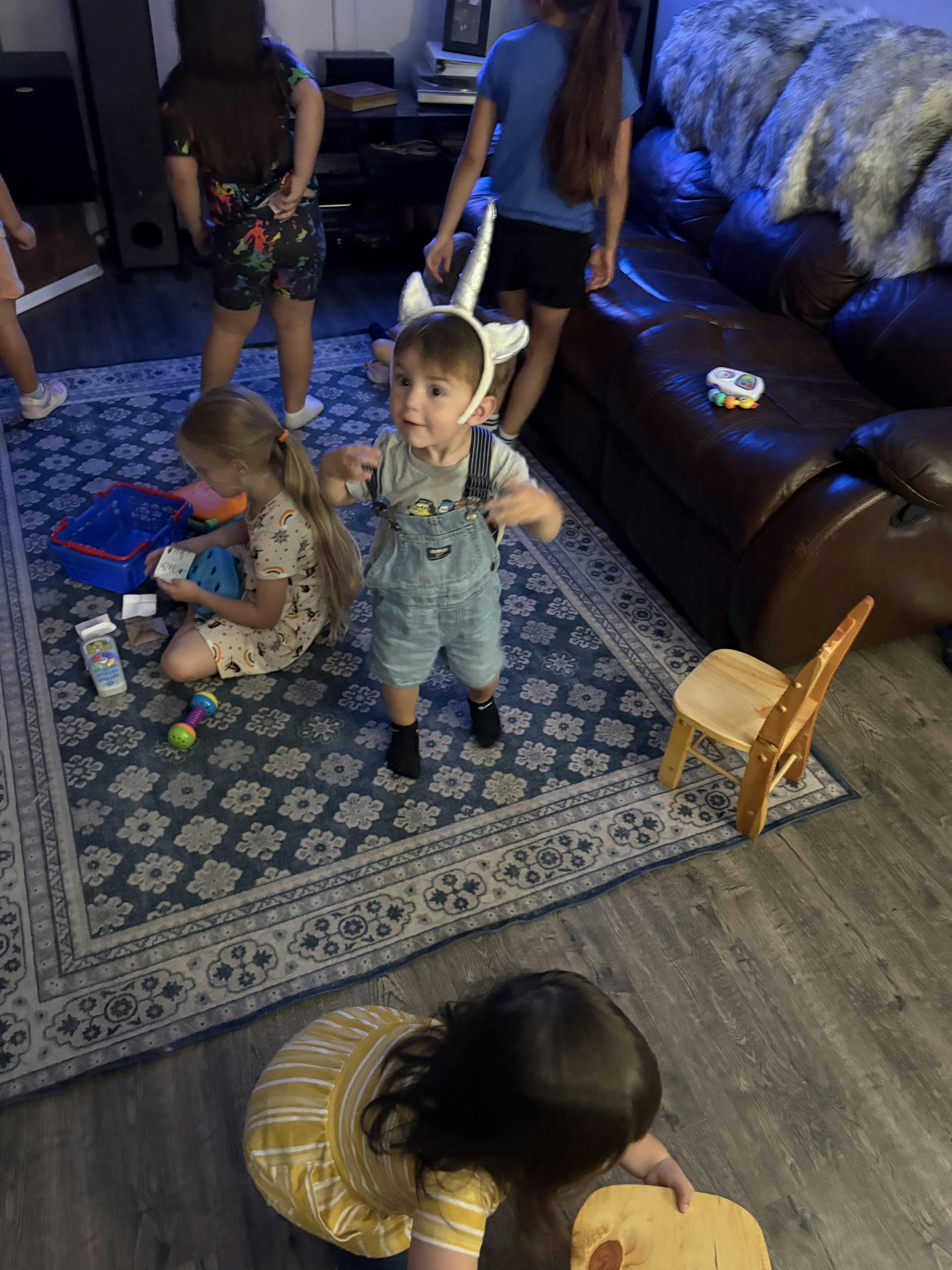 Child wearing a unicorn headband standing among other children playing