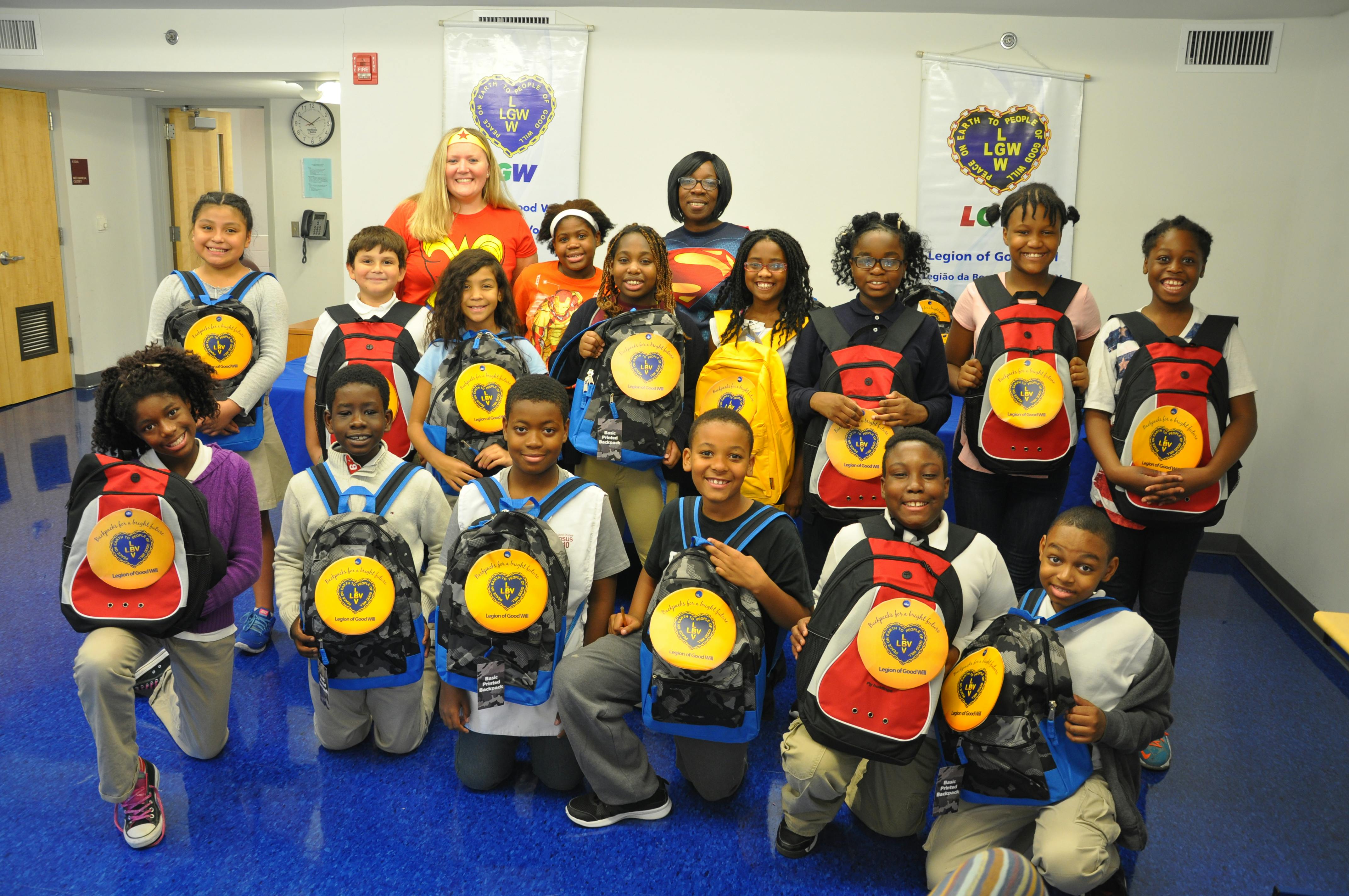 Group of children and adults posing with new backpacks, some kneeling