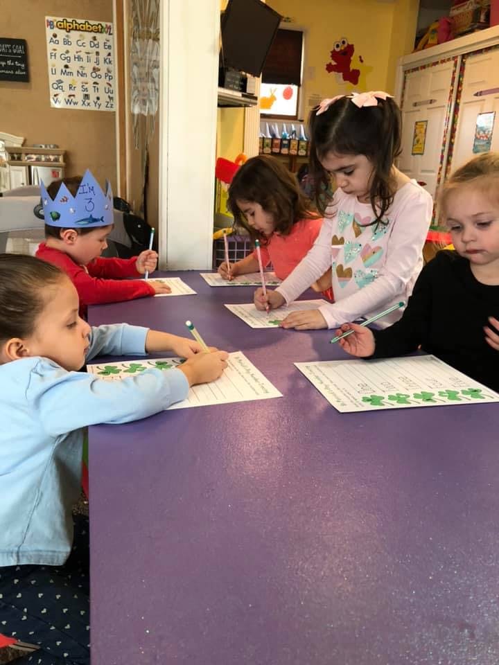 Children writing at a table in a classroom