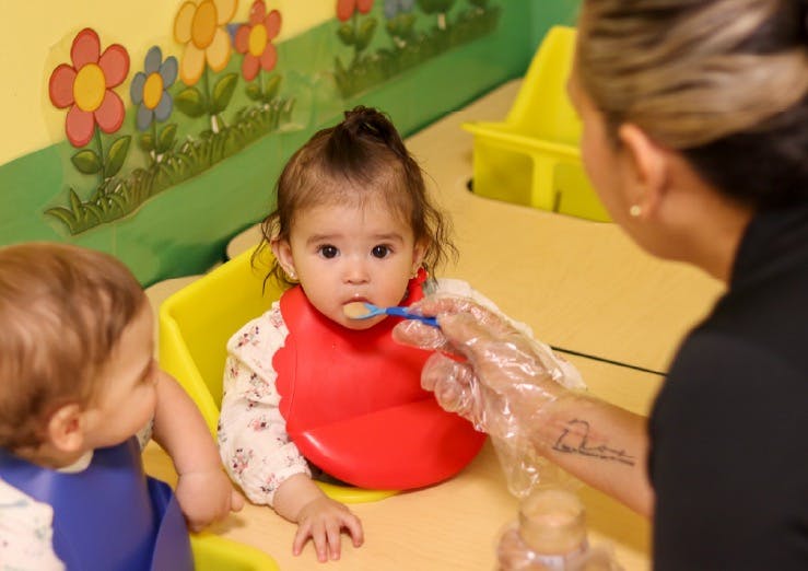 A person using a spoon to feed a child sitting at a table