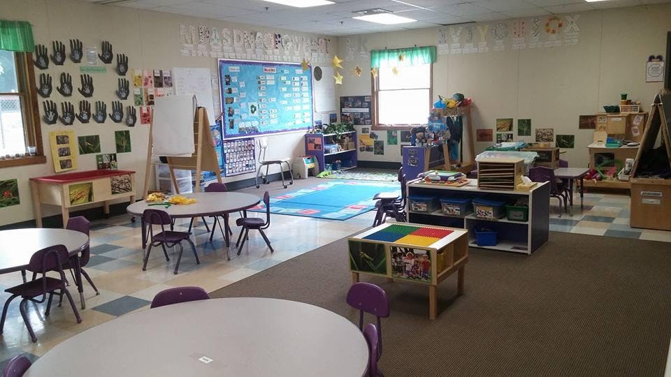 Empty colorful preschool classroom with tables, chairs, and learning materials
