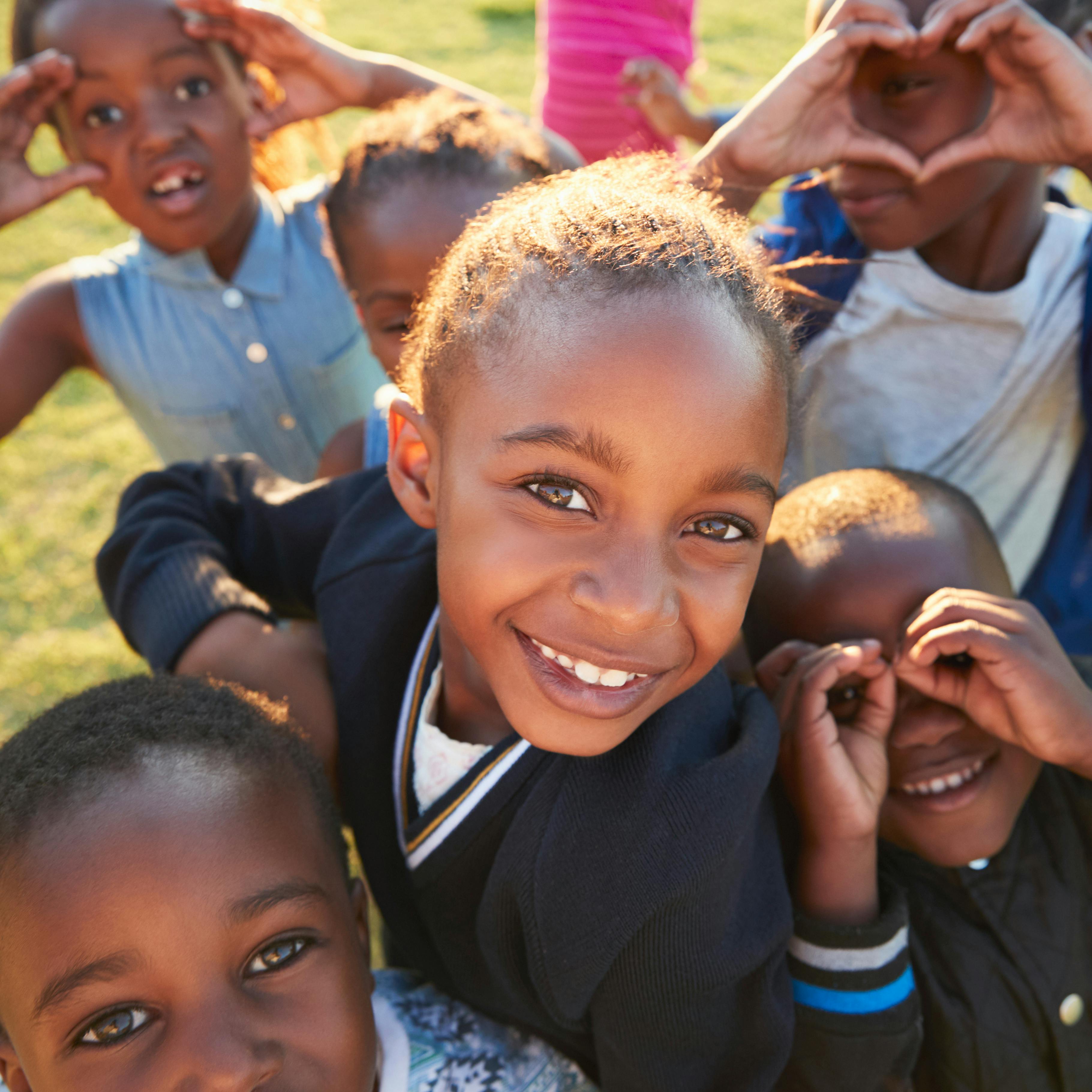 Children making playful faces and hand gestures, with one child smiling at the camera