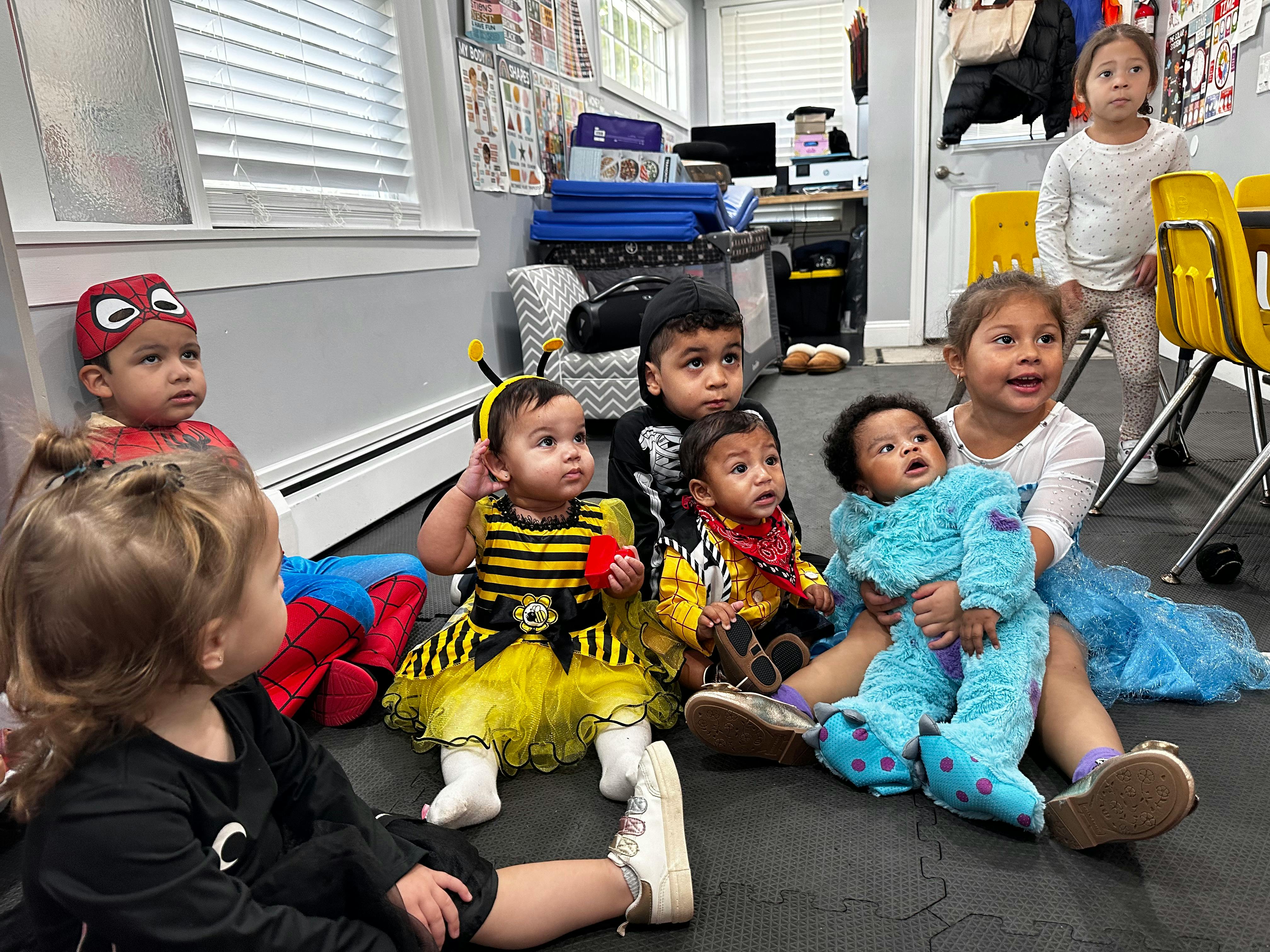 Group of children and babies in costumes sitting on the floor