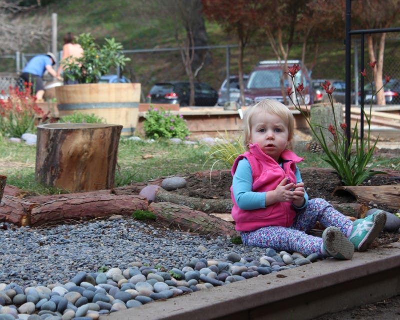 Child sitting on the ground next to a gravel path