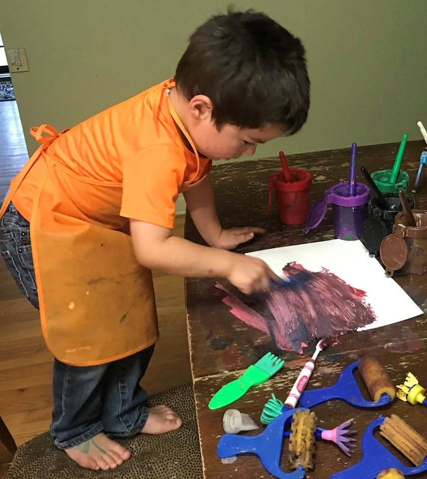 Child in an apron painting on paper with a brush