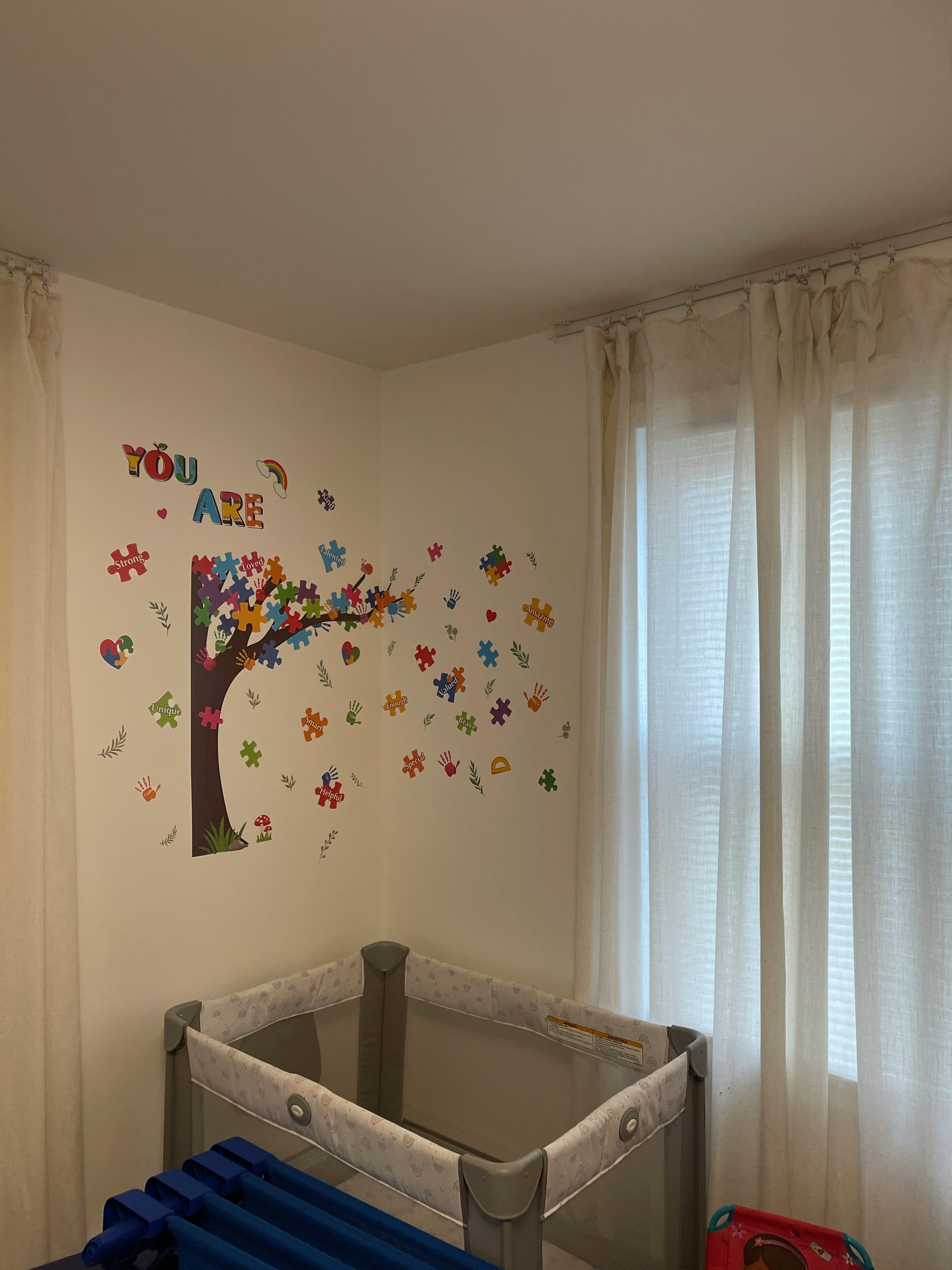 White wall with a tree-like decal made of colorful puzzle pieces, text reads "YOU ARE"
