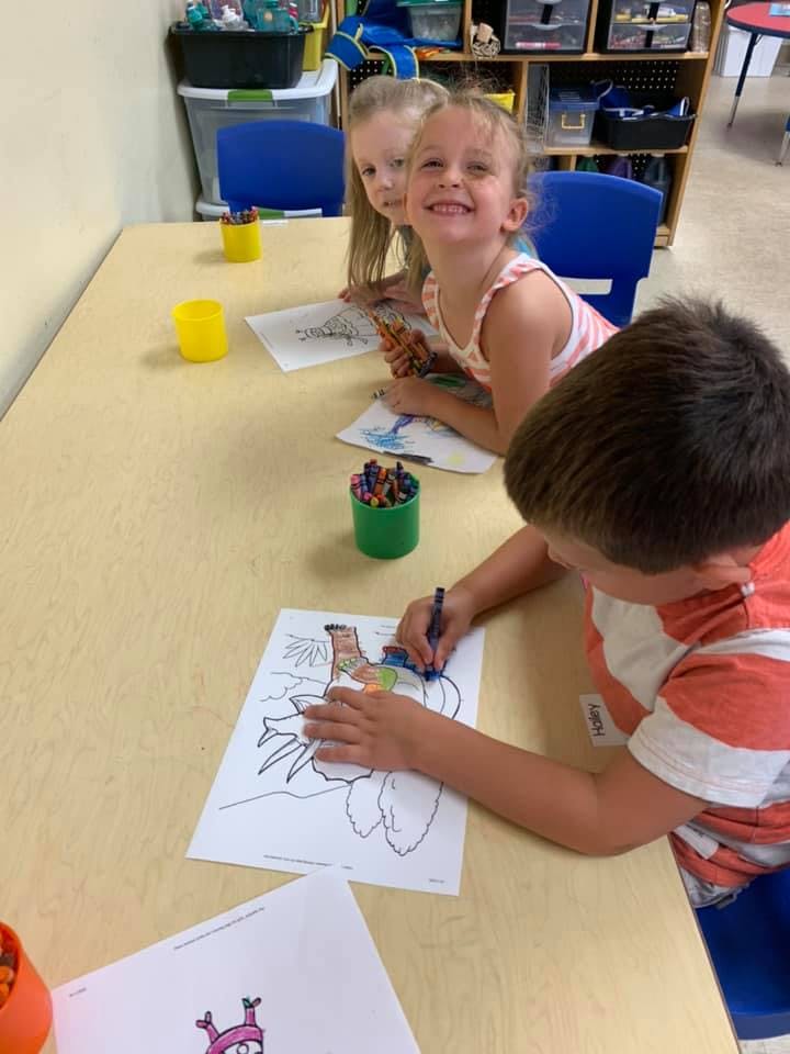Children coloring at a table in a classroom