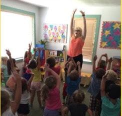 Adult and children raising arms in a classroom
