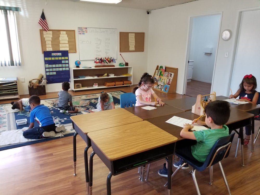 Children working at desks and on the floor in a classroom
