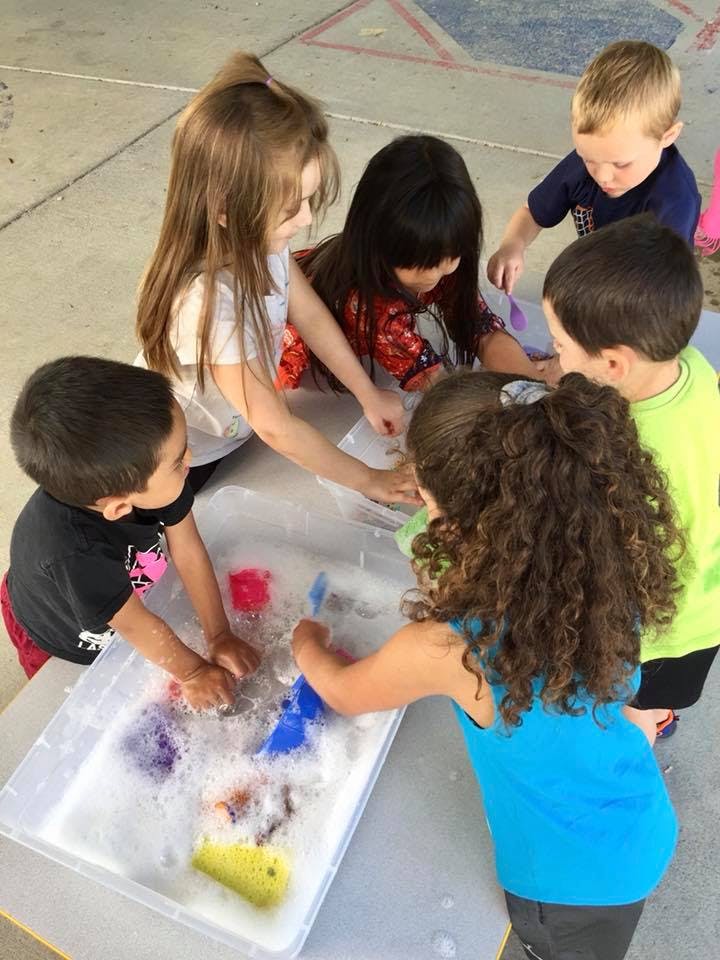 Children playing with toys in a tub of soapy water