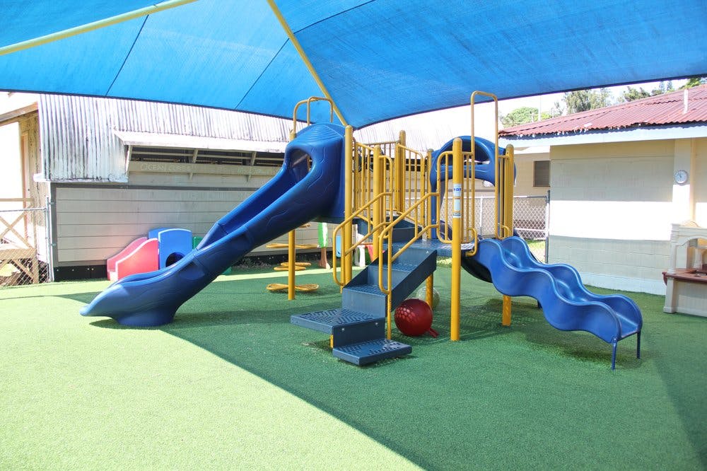 Playground with blue slides and yellow railings under a blue shade canopy