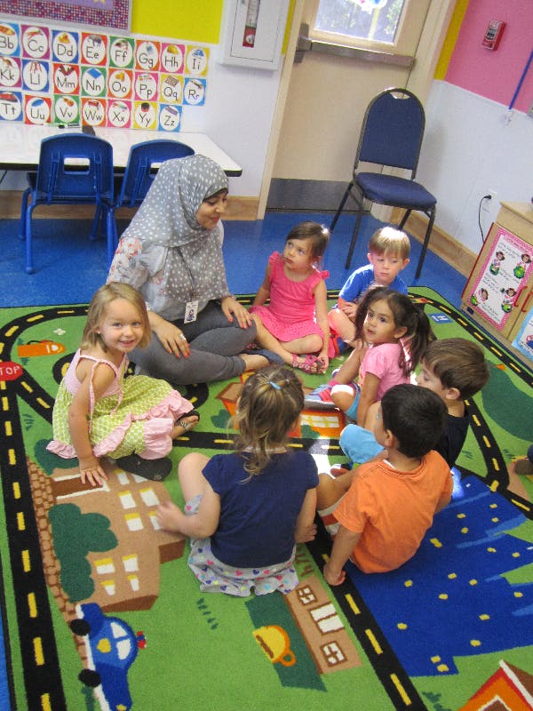 Adult and children sitting on a rug in a classroom