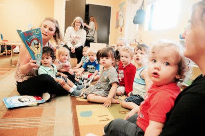 Person reading a book to a group of children sitting on the floor