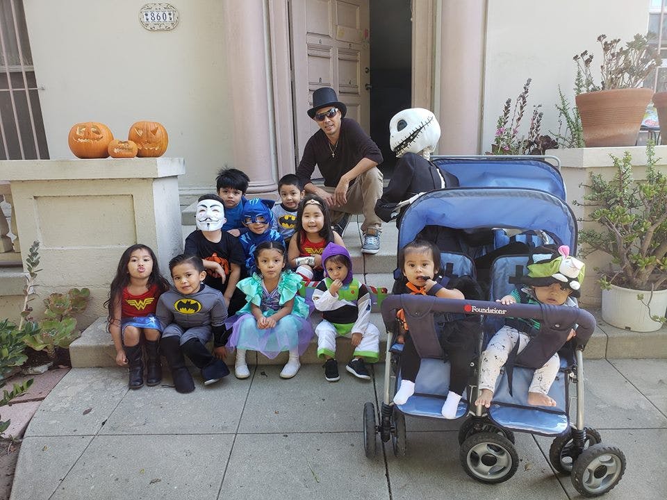 People and children in costumes posing on steps with pumpkins