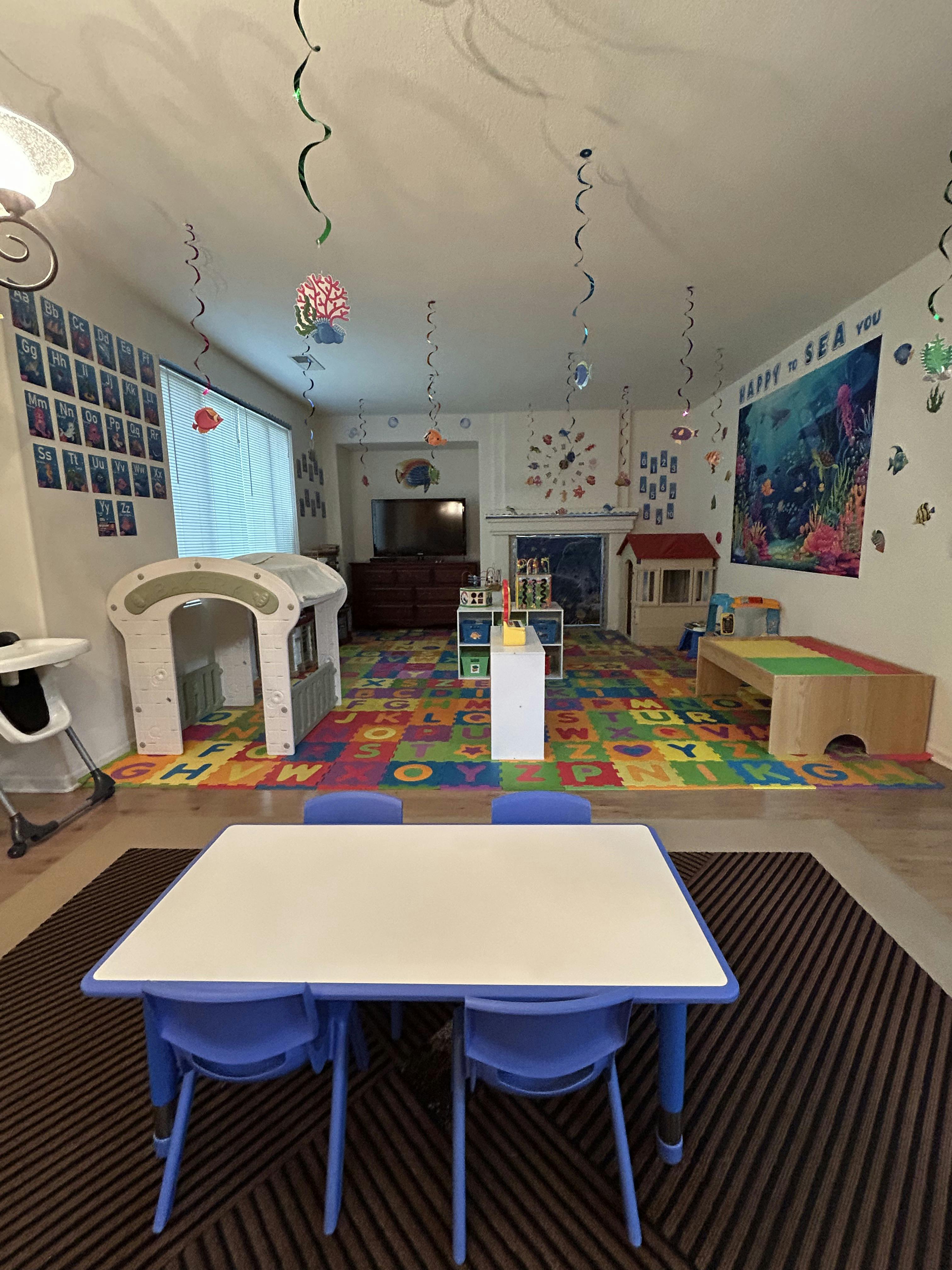 Playroom with colorful alphabet rug, small table and chairs, and play structures