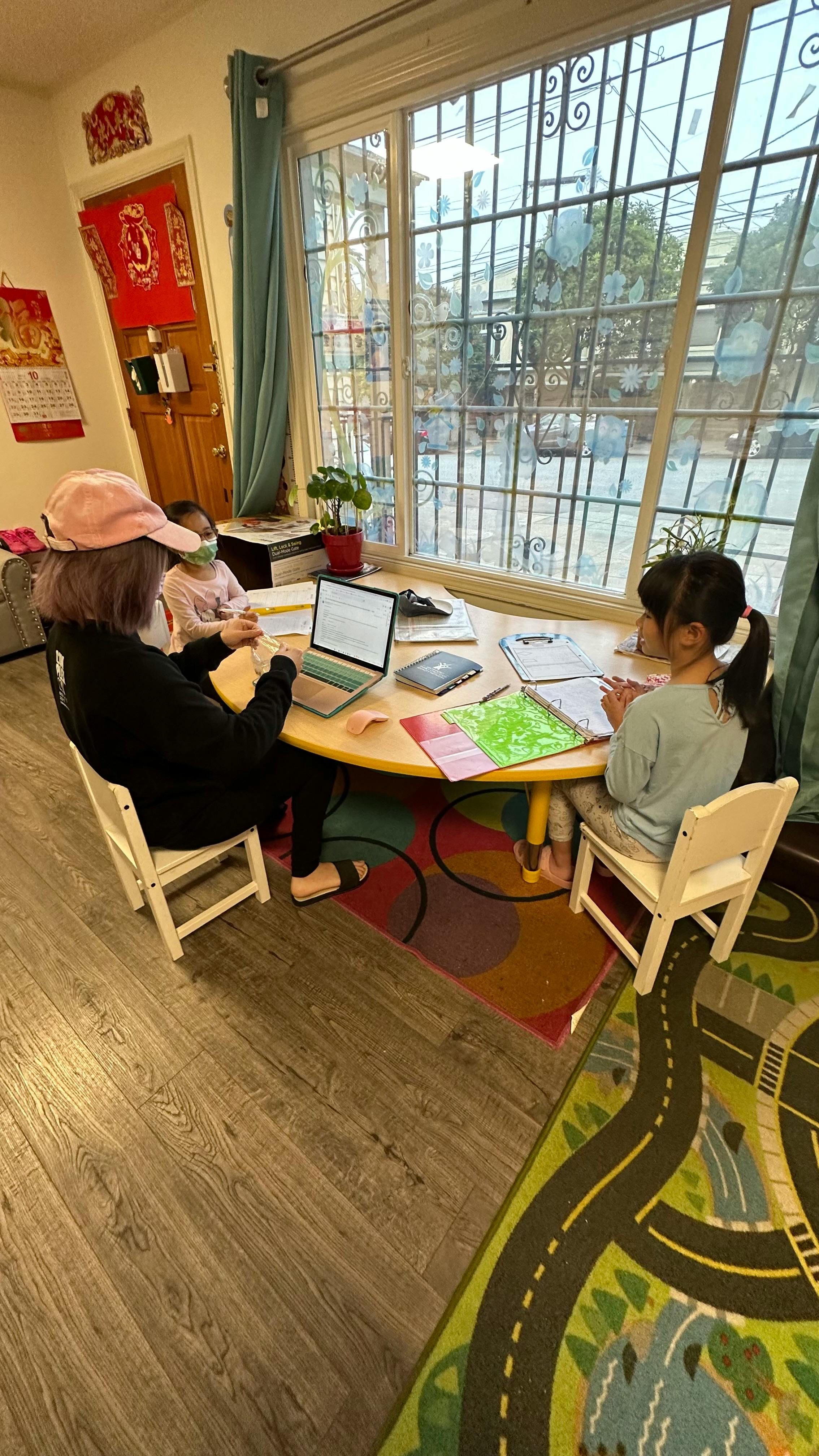 Person and child at a table with a laptop and notebooks