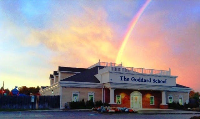 The Goddard School building with a rainbow in the sky
