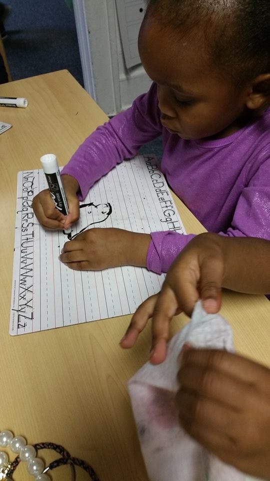 Child drawing on a paper with alphabet letters