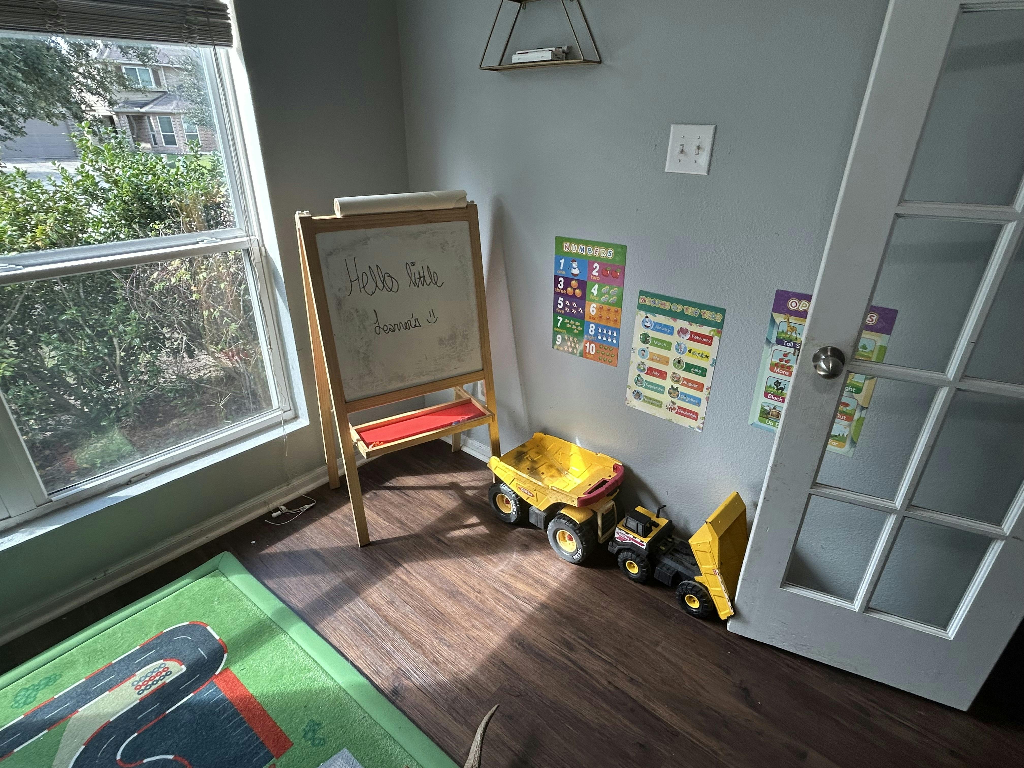 Playroom with an easel, educational wall posters, and toy dump trucks