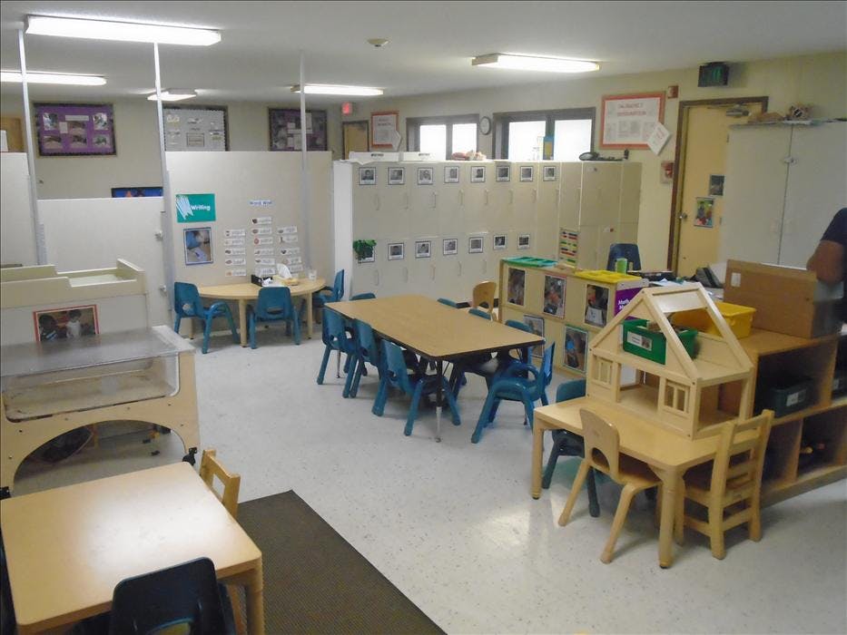 Empty classroom with multiple tables, chairs, and learning stations