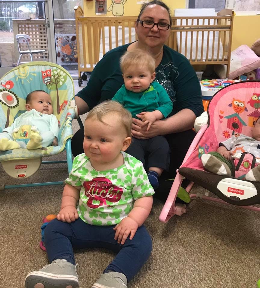 Person holding a child, with two other children in baby seats