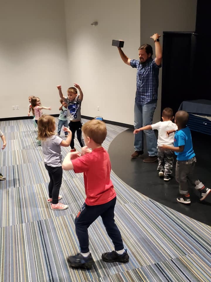 Adult and children dancing in a room