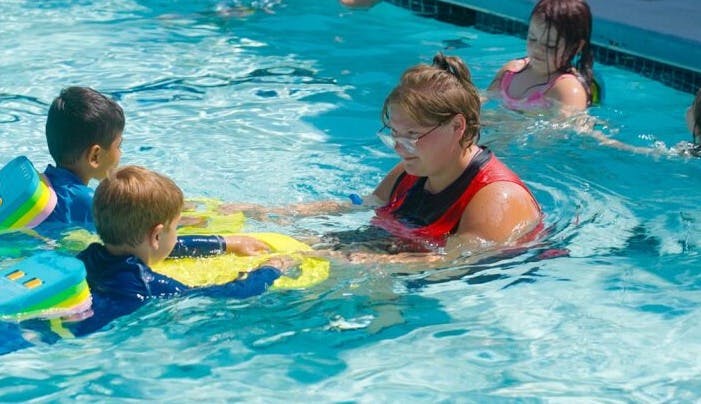 adult with children in a swimming pool during a swim lesson