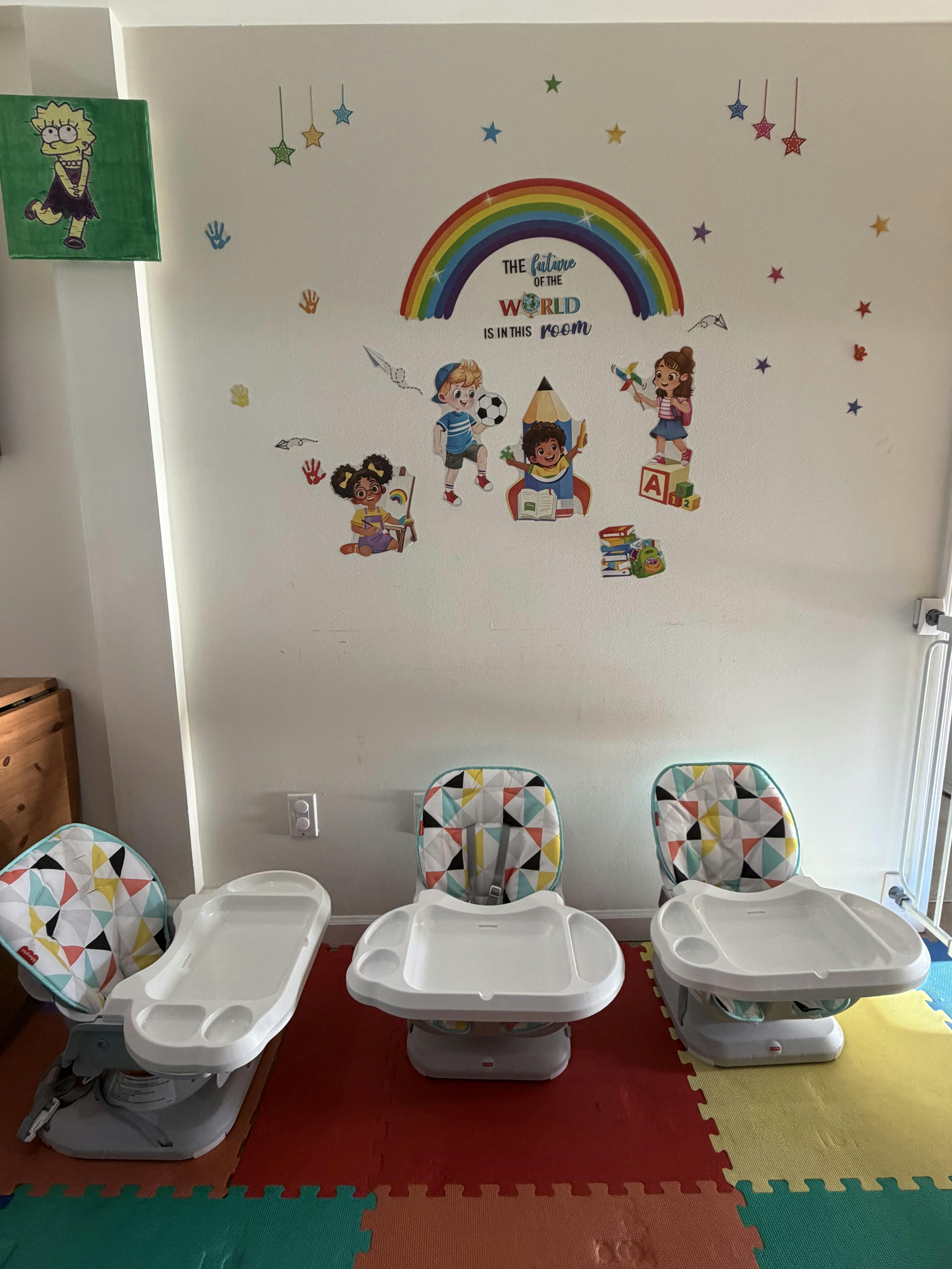 Three baby booster seats arranged in a row in front of a decorated wall