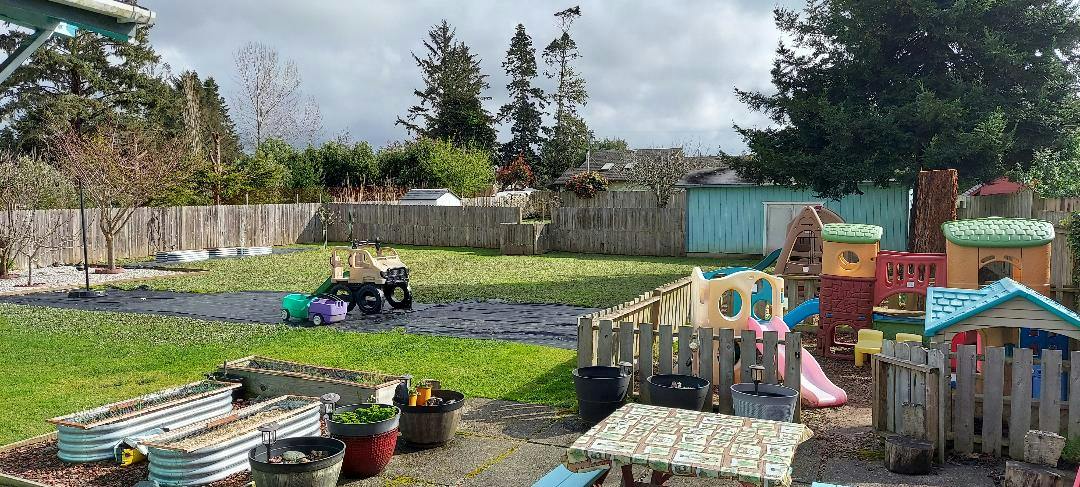 Backyard with garden beds, a toy truck, and a plastic play structure