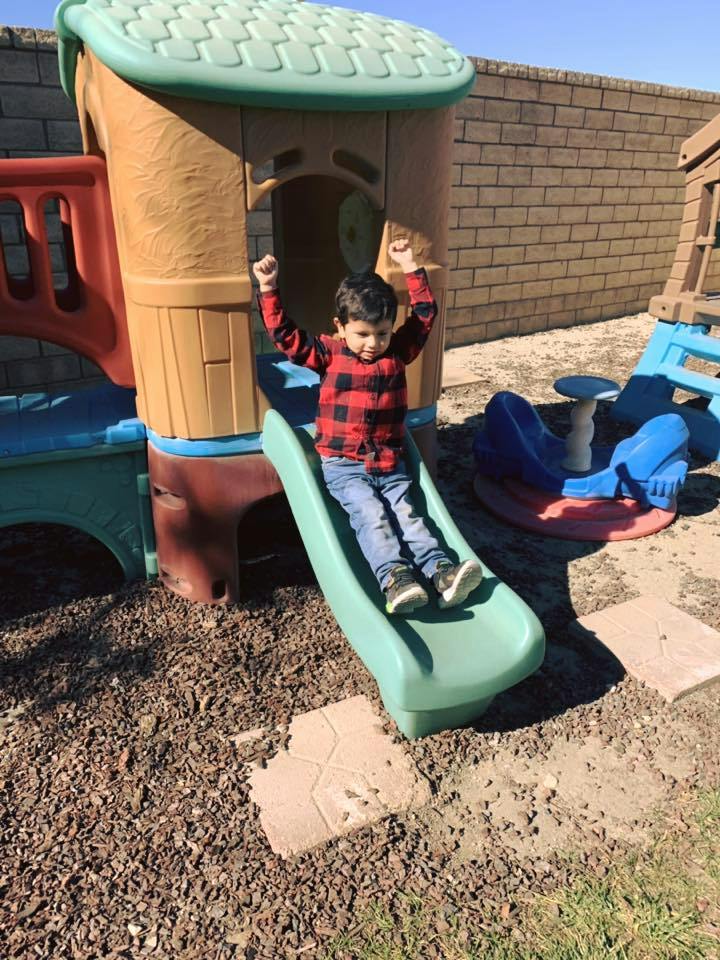 Child on a slide with arms raised