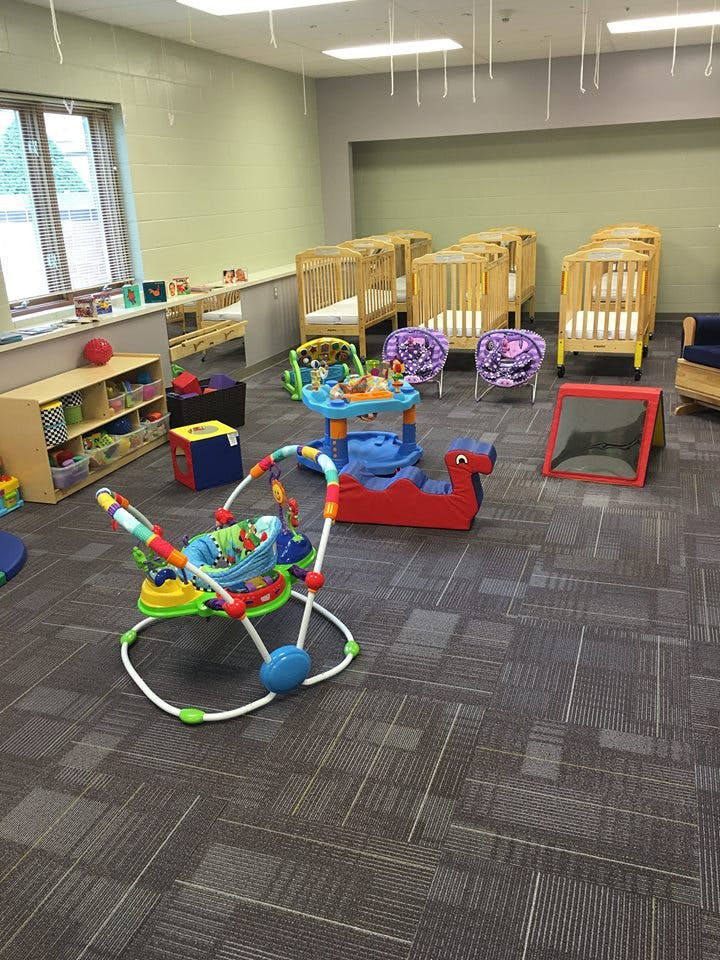 Nursery room with multiple cribs, a baby bouncer, and other toys