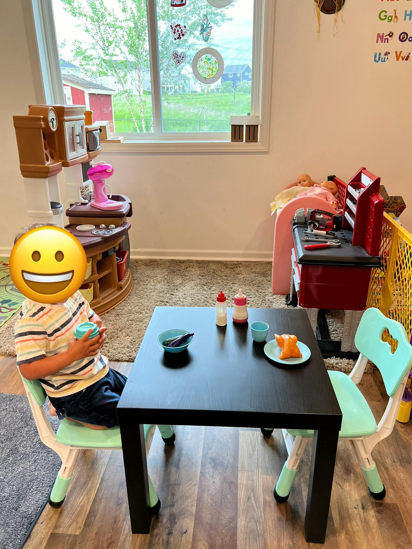 Child sitting at a small table with a plate and cup
